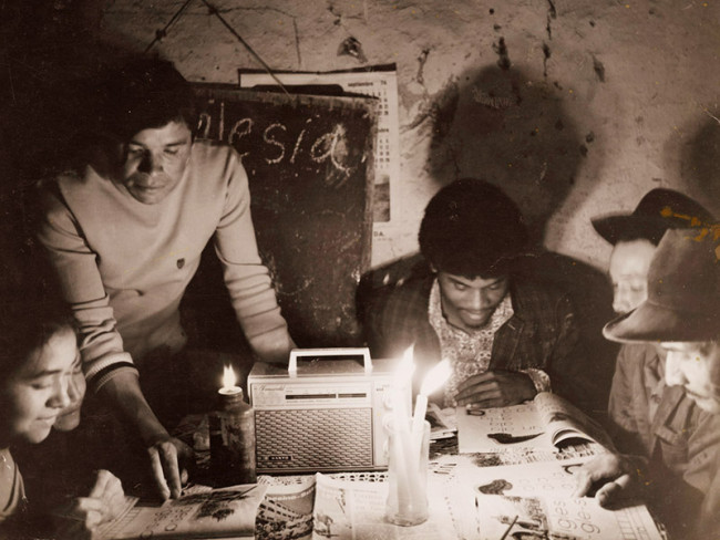 Colombian farmers hudled over a radio listening to Radio Sutatenza.