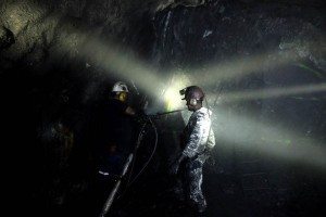 Headlamps illuminate glittering veins of green in the rock